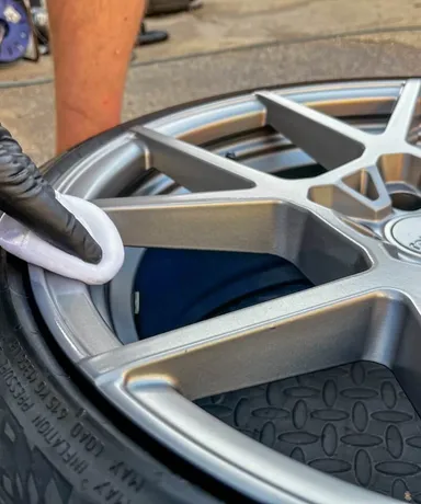 White pad with ceramic coating being applied to gray alloy wheel