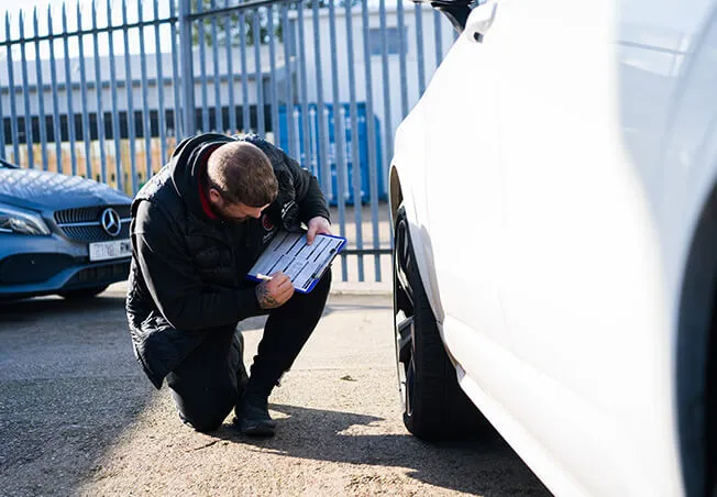 Rolling Rims employee checking the alloy wheels of the lease car and filling out the report sheet